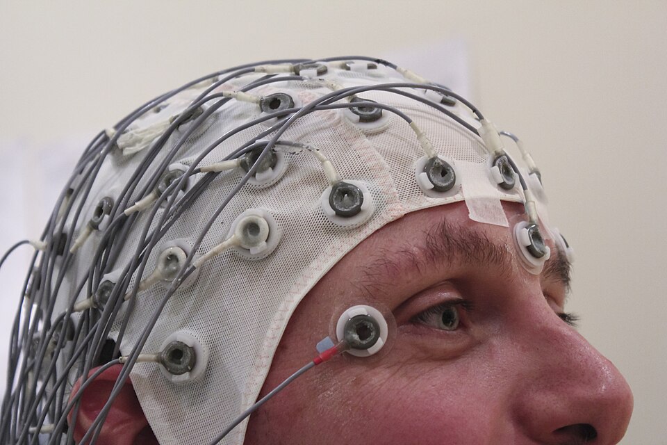 A person wearing a fabric cap studded with EEG electrodes.
