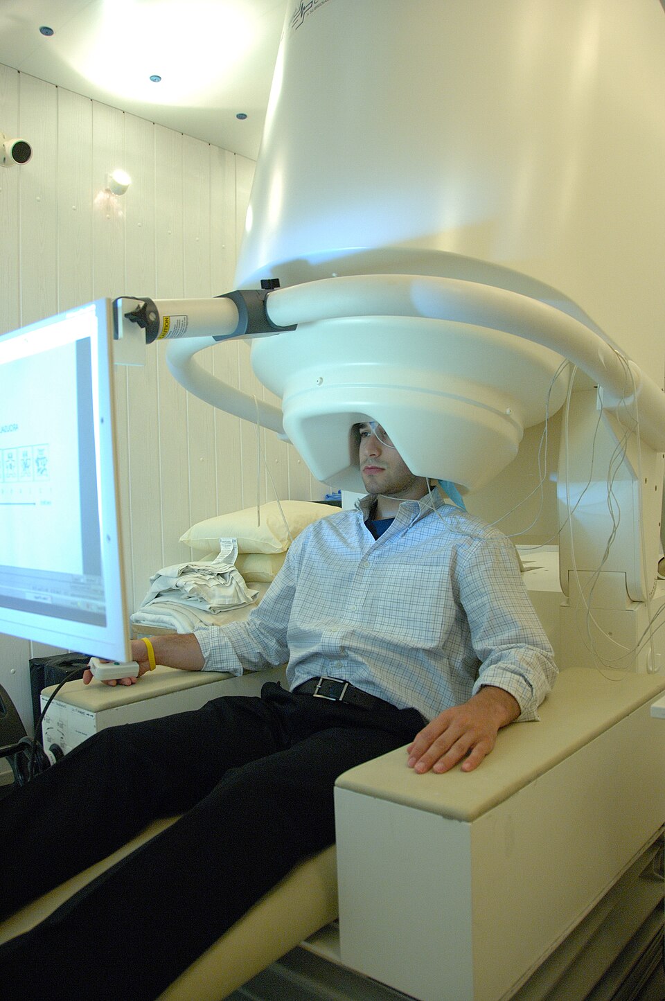 A magnetoencephalography scanner: a seat beneath a large white helmet-shaped sensor housing.